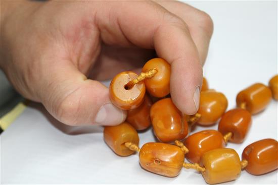 A single strand barrel shaped amber bead necklace, 86cm.